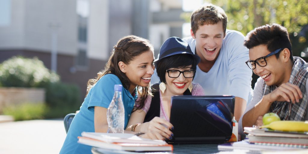 Students using laptop together outdoors